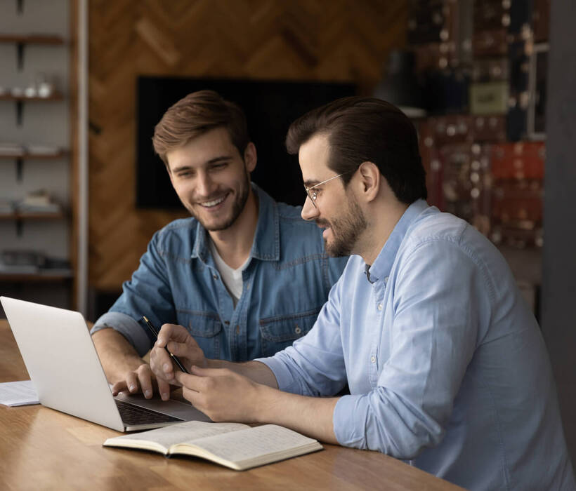 Mitarbeiter teilen sich einen Laptop, diskutieren über ein Projekt, arbeiten zusammen und sehen sich ein Online-Training an.