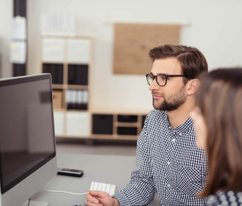 zwei mitarbeiter im büro schauen auf computer